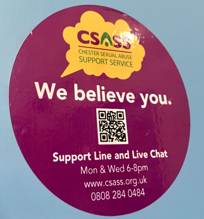 Photo of round toilet door stickers in a big roll.  They are purple with the CSASS logo, a QR code and #webelieveyou printed on them.